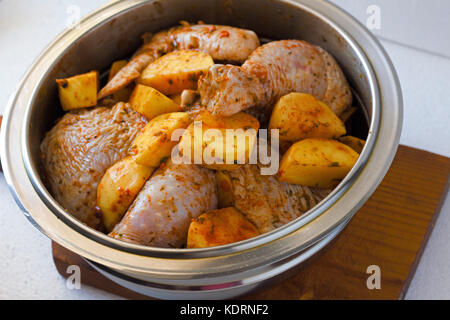 Raw Hähnchenschenkel mit rohen Kartoffeln mit Gewürzen zum Backen auf einem Holztisch. Fleisch Zutaten zum Kochen. Stockfoto