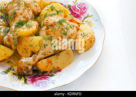 Platte mit Huhn und Kartoffeln auf weißem Hintergrund Stockfoto