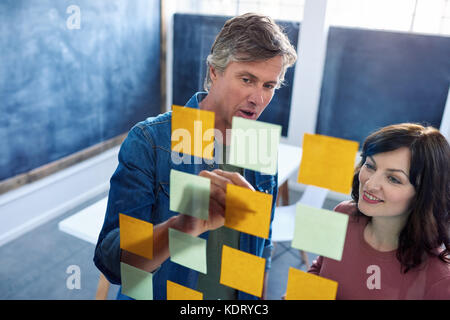 Lächelnd Mitarbeiter Brainstorming über eine Glaswand in einem Büro Stockfoto