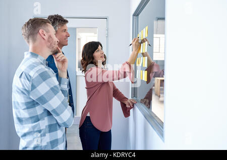 Lächelnd Kollegen Brainstorming mit Haftnotizen in einem modernen Büro Stockfoto