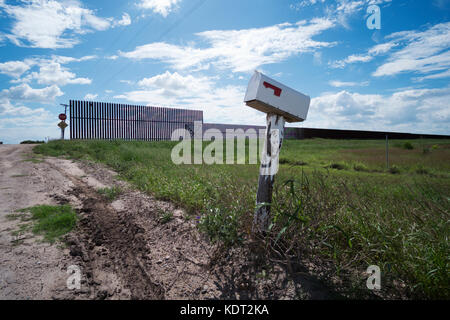 Texas Grenzzaun sitzt auf einem Deich, in der Nähe von Texas an der mexikanischen Grenze mit einem Bauern Mailbox in den Vordergrund. Dieser Teil des Zauns wurde während gebaut Stockfoto