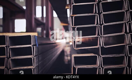 Metal pipe profile and sun in the background. Sheet metal profiles transporting, close up. Metal or aluminum profile channel for use in structures, warehouse. Bent metal profile channel. Factory Stockfoto