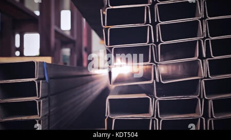 Metal pipe profile and sun in the background. Sheet metal profiles transporting, close up. Metal or aluminum profile channel for use in structures, warehouse. Bent metal profile channel. Factory Stockfoto