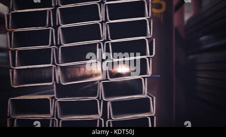 Metal pipe profile and sun in the background. Sheet metal profiles transporting, close up. Metal or aluminum profile channel for use in structures, warehouse. Bent metal profile channel. Factory Stockfoto