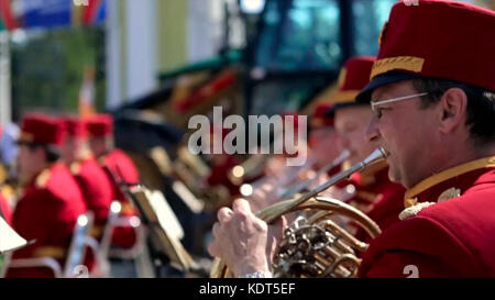 Russland, Moskau - 12. Juni 2017: Bandmeister auf einer Trompete. Bandwalas spielen auf ihren Instrumenten im Park. Männer in Rot spielen die Trompete aus der Nähe. Stockfoto