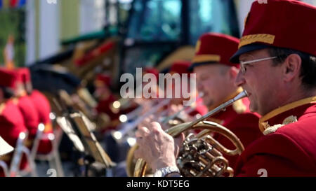 Russland, Moskau - 12. Juni 2017: Bandmeister auf einer Trompete. Bandwalas spielen auf ihren Instrumenten im Park. Männer in Rot spielen die Trompete aus der Nähe. Stockfoto