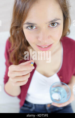 Junge Frau mit einem Glas Wasser und einer Pille Stockfoto