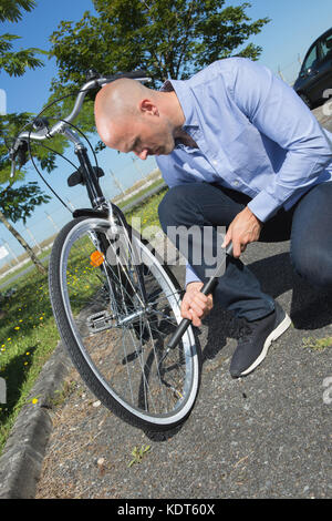 Man Aufpumpen der Reifen auf seinem Fahrrad im Park Stockfoto