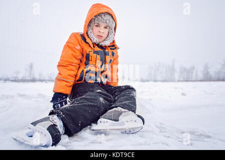 An Training junge jugendlich auf Schnee in der Nähe von Schlittschuhlaufen eisbahn im Hockey Skate müde. Konzept der Ausbildung auf Eis. Stockfoto