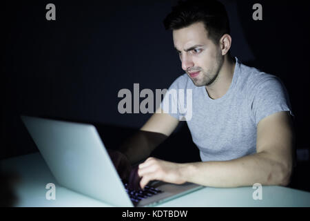 Nacht Internet sucht oder Arbeit spät Mann mit Laptop an einem Schreibtisch in der Dunkelheit Stockfoto