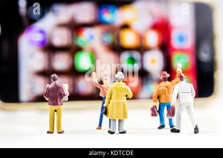 Geschäftskonzept, Nahaufnahme von minifigürchen von Geschäftsleuten steht vor großen Defokussierten Bildschirm des Smartphones Stockfoto