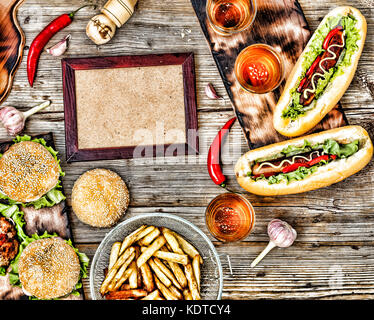 Im rustikalen Stil, Ansicht von oben hausgemachte Burger mit Rindfleisch, Hot Dogs und Bier auf einer hölzernen Tisch. Stockfoto