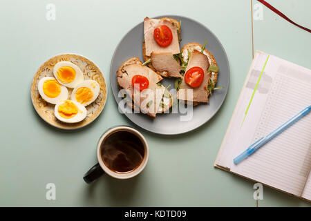 Gesundes Frühstück Sandwiches mit Schinken, Rucola, Butter, Kirschtomaten und hart gekochte Eier, schwarz bio Kaffee Stockfoto