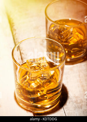 Zwei Gläser Whisky mit Eiswürfel auf einem weißen Brettern serviert. Stockfoto