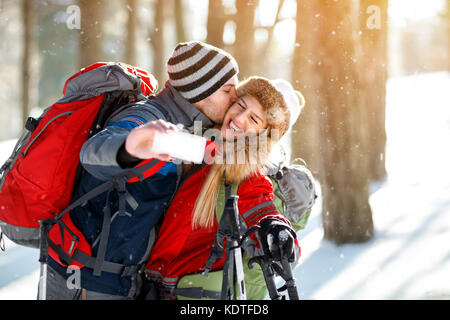 Junge Skifahrer küssen, während Sie selfie im Wald Stockfoto