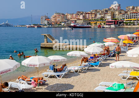 Saranda Strand weißer Schirme und die Skyline der Stadt Vlore, Sarande, Grafschaft, Albanien. Stockfoto