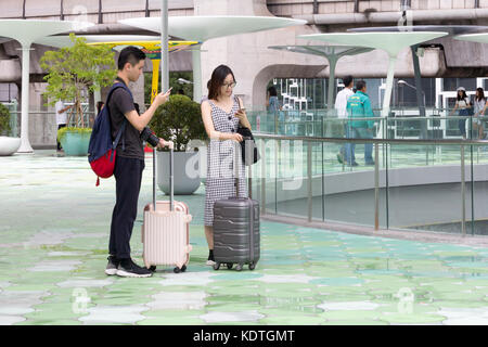 Asiatische Paar mit Koffern Consulting ihre Telefone für Richtungen, Bangkok, Thailand Stockfoto