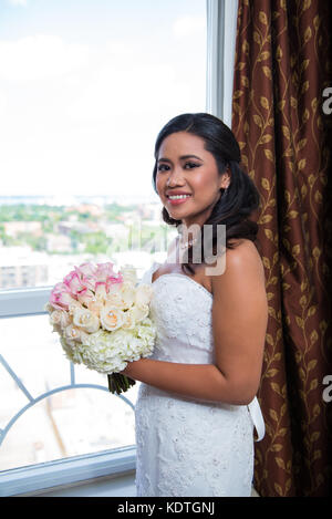 Schönen lächeln Braut an Fenster mit Blumenstrauß Stockfoto