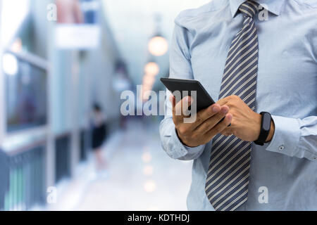 Isolierte Geschäftsmann mit smart Armband und Smartphone auf Shopping mall Hintergrund Stockfoto