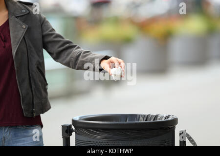 Nahaufnahme einer Dame hand Müll werfen Sie einen Papierkorb auf der Straße Stockfoto