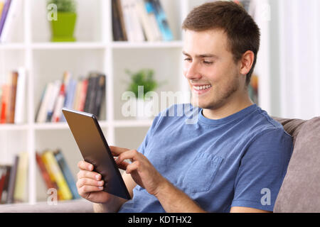 Glückliche Menschen mit einem Tablet auf einem Sofa zu Hause sitzen Stockfoto