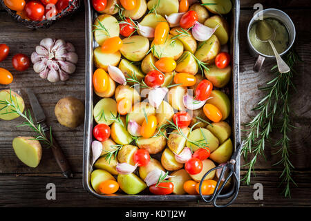 Zutaten für gebratene hausgemachte Kartoffeln mit Tomaten, Knoblauch und Rosmarin Stockfoto