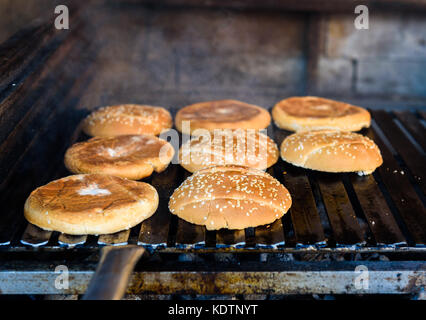 Und grillen Hamburger Brötchen Mit Sesam auf Kohle Grill. Vorbereitung geröstet Essen am Grill BBQ Grill, Feuerstelle und u-form Feuer Grid. Stockfoto