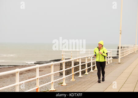 Aberystwyth, Ceredigion, Wales, Großbritannien. 16. Oktober 2017. Wetter in Großbritannien. An der Küste von West Wales in Aberystwyth zieht es starke Winde, wenn sich der Sturm Ophelia nähert - ein Jogger auf der Promenade hält ein Auge auf den Sturm, der vor der Irischen See einzieht. Quelle: Steven May/Alamy Live News Stockfoto