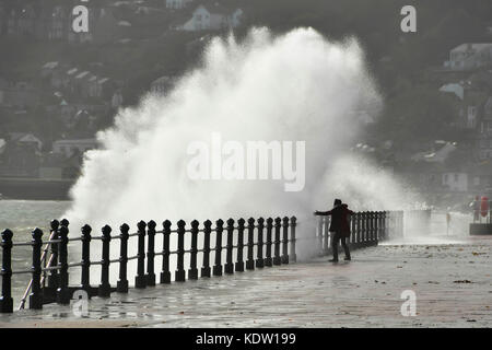 Penzance, Cornwall, UK. 16. Oktober 2017. UK Wetter. Ein Nervenkitzel sucht Frau erhält eine Tiefe, wie Sie vor einem plätschernden Wellen, die auf der Promenade von Penzance in Cornwall, der von Gale force Winds aus ex Hurrikan Ophelia gepeitscht wurde. Photo Credit: Graham Jagd-/Alamy leben Nachrichten Stockfoto