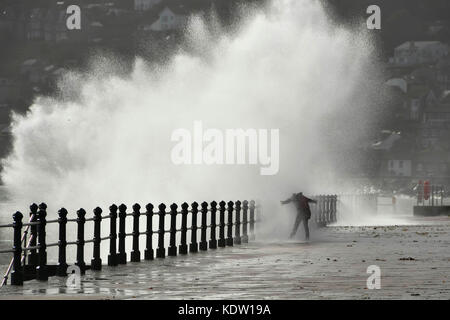 Penzance, Cornwall, UK. 16. Oktober 2017. UK Wetter. Ein Nervenkitzel sucht Frau erhält eine Tiefe, wie Sie vor einem plätschernden Wellen, die auf der Promenade von Penzance in Cornwall, der von Gale force Winds aus ex Hurrikan Ophelia gepeitscht wurde. Photo Credit: Graham Jagd-/Alamy leben Nachrichten Stockfoto