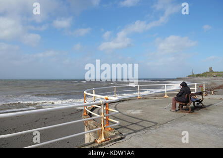 Aberystwyth, Ceredigion, Wales, Großbritannien. 16. Oktober 2017. Wetter in Großbritannien. Eine Frau sitzt und beobachtet, wie starke Winde über 50mph am Strand von Aberystwyth steigen - die starken Winde kommen aus dem Südwesten über die Irische See an der Küste von West Wales, als sich der Sturm Ophelia nähert - Foto Steven May / Alamy Live News Stockfoto