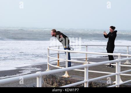 Aberystwyth, Ceredigion, Wales, UK. 16 Okt, 2017. de Wetter. Junge Freunde Spaß auf der Promenade lehnte sich in den starken Winden am Aberystwyth auf der West Wales Küste als Sturm Ophelia aus Ansätze der Irischen See mit lokalen Winden von mehr als 50 km/h. foto Steven Mai/alamy leben Nachrichten Stockfoto