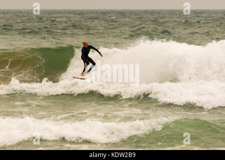 Surfer auf einer Welle in großen Wellen und starke Winde von Sturm, ex - Hurrikan Ophelia in Boscombe Strand, Bournemouth, Dorset, Großbritannien, Oktober 2017. Stockfoto