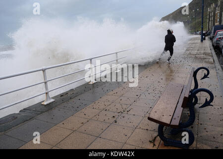 Aberystwyth, Ceredigion, Wales, UK-Flut kommt mit Sturm Ophelia offshore über die Irische See - ein Mann erhält durchnäßt, als der Sturm das Meer Wimpern - Peebles und Kies fliegen auf der Promenade-stong Winde in Aberystwyth auf der West Wales Küste als Sturm Ophelia Ansätze aus der Irischen See mit lokalen Winden von mehr als 50 km/h. Foto Steven Mai/Alamy leben Nachrichten Stockfoto