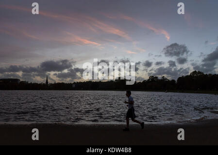 London, Großbritannien. 16. Oktober 2017. UK Wetter: Sonnenuntergang über dem runden Teich im Park Kensington Gardens. Staub durch Winde aus Hurrikan Ophelia brachte verursacht die Sonne eine geheimnisvolle Farbe orange gegen einen rötlichen Himmel erscheinen. Credit: Stephen Chung/Alamy leben Nachrichten Stockfoto