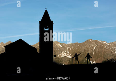 Silhouetten von Wanderern an der alten Kirche bei Sonnenaufgang, Alp San Romerio, Brusio, Kanton Graubünden, Poschiavo, Schweiz Stockfoto