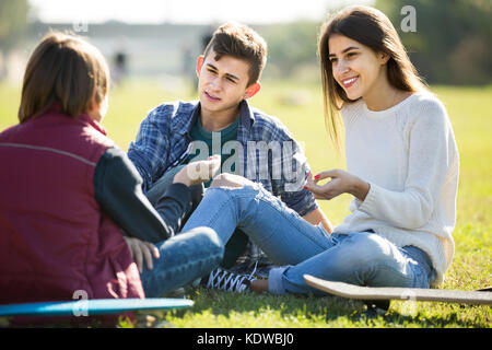 Drei Jugendliche heraus hängen draußen und etwas diskutieren Stockfoto