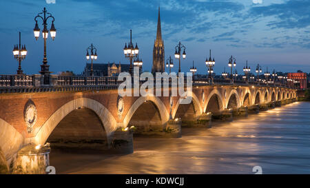 Pont de Pierre überspannt den Fluss Garonne in der Dämmerung mit Basilika Saint-Michel jenseits, Bordeaux, Aquitaine, Frankreich Stockfoto