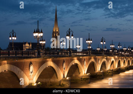 Pont de Pierre überspannt den Fluss Garonne in der Dämmerung mit Basilika Saint-Michel jenseits, Bordeaux, Aquitaine, Frankreich Stockfoto