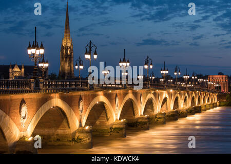 Pont de Pierre überspannt den Fluss Garonne in der Dämmerung mit Basilika Saint-Michel jenseits, Bordeaux, Aquitaine, Frankreich Stockfoto
