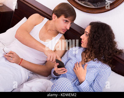 Die jungen Eheleute im Schlafanzug besetzt mit Smartphones separat im Bett Stockfoto