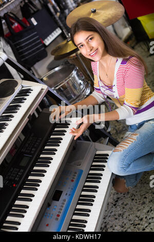 Lächelnd langhaarige Teenager Auswahl Synthesizer in Store Stockfoto