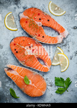 Frischer Lachs Filet in Scheiben flach auf schäbige Metall Hintergrund legen. roher Lachs filet und Zutaten Petersilie, Basilikum, Fenchel, Pfeffer Mais und Stockfoto