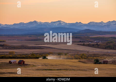 Die Wolken fangen den Sonnenuntergang über den Ausläufern westlich von Calgary, wo die Felder geerntet werden. Stockfoto