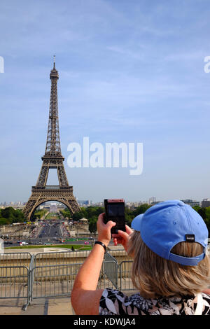 Eine weibliche Touristen nimmt ein Foto auf den Eiffelturm in Paris an einem Sommertag Stockfoto