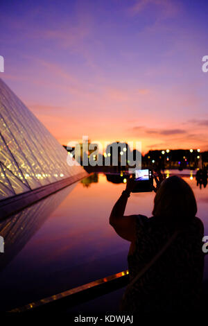 Eine Frau touristische nimmt ein Foto des Louvre in der Nacht in Paris, können Sie über Ihr Smartphone Stockfoto