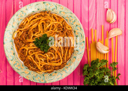 Italienische Art spaghetti bolognese Essen mit einem reichhaltigen Rindfleisch Soße auf einem rosa Hintergrund Holz Stockfoto