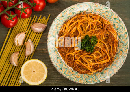 Italienische Art spaghetti bolognese Essen mit einem reichhaltigen Rindfleisch Soße auf einer grünen Holz- Hintergrund Stockfoto