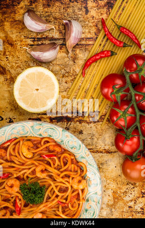 Im italienischen Stil würzige Garnelen oder Shrimps Spaghetti in einem Chili Tomatensauce auf einem distressed Backofen oder Backblech Stockfoto