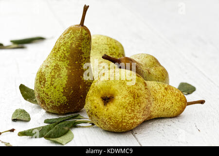 Vier Abate Fetel Birnen mit Blättern auf weiß lackiertes Holz. Stockfoto